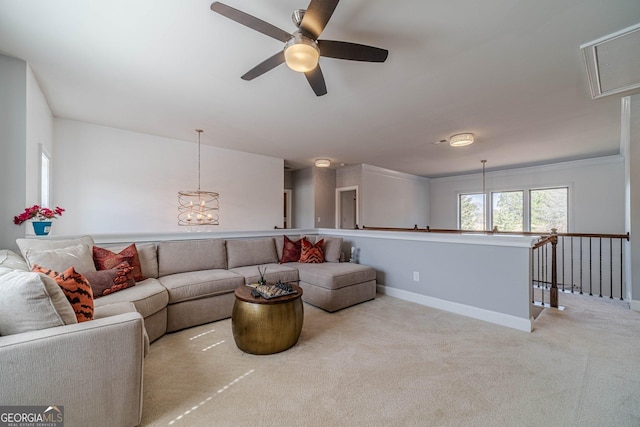 living area with carpet flooring, ceiling fan with notable chandelier, attic access, and baseboards