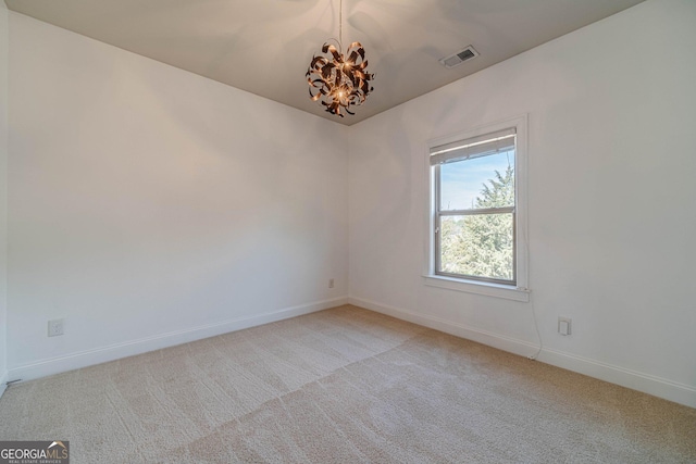 spare room featuring visible vents, light colored carpet, baseboards, and an inviting chandelier