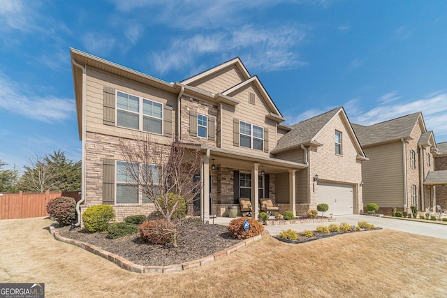 craftsman house featuring stone siding, fence, covered porch, concrete driveway, and a garage