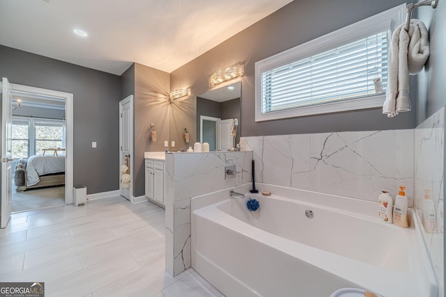 ensuite bathroom with ensuite bath, baseboards, vanity, and a garden tub