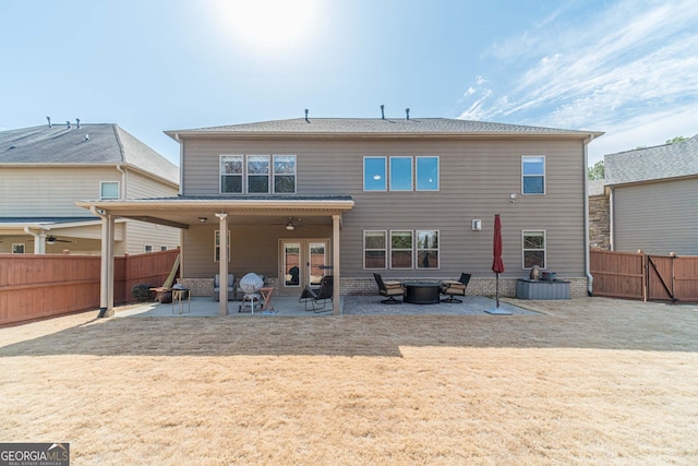 back of property with a yard, a patio, a fenced backyard, and an outdoor fire pit