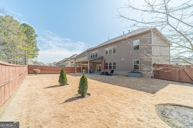 rear view of house with a fenced backyard and a patio