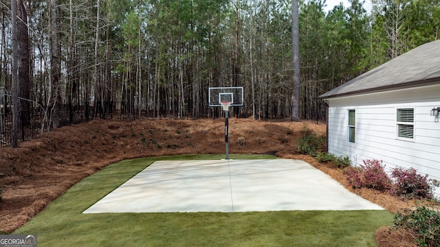 view of sport court with a lawn and basketball hoop