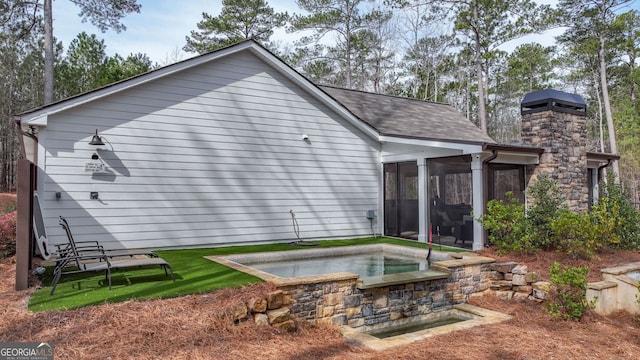 back of property with roof with shingles and a sunroom