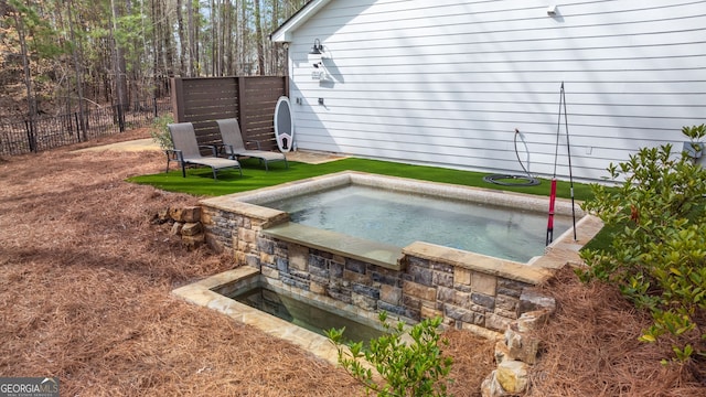 view of swimming pool with an in ground hot tub and fence