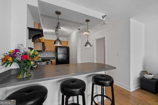 kitchen featuring tasteful backsplash, dark countertops, a peninsula, and a textured ceiling