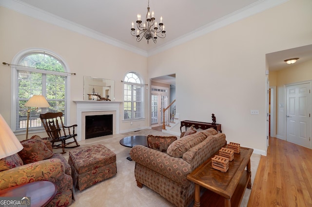 living room with plenty of natural light, an inviting chandelier, light wood-style flooring, and crown molding