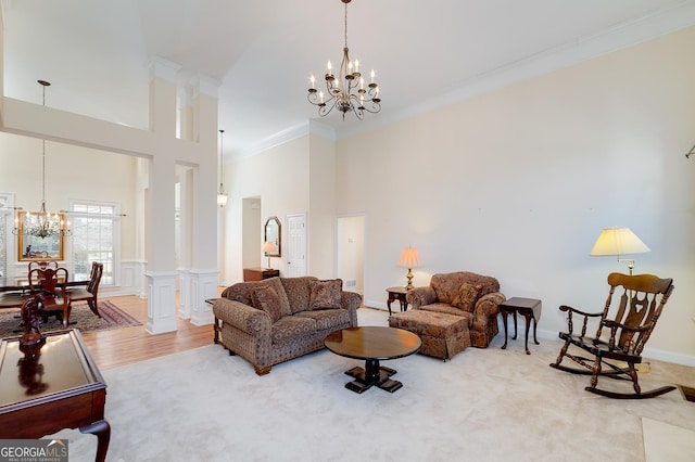 living room with a wainscoted wall, wood finished floors, a towering ceiling, crown molding, and a chandelier