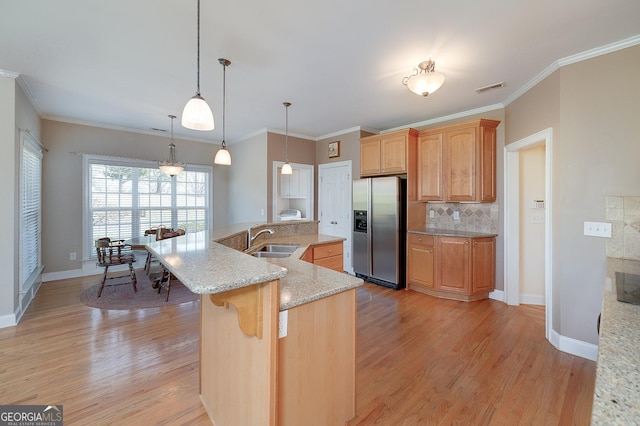 kitchen featuring a sink, backsplash, stainless steel refrigerator with ice dispenser, and light wood finished floors