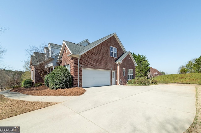 view of side of home featuring an attached garage, brick siding, and driveway