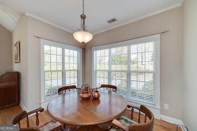 dining room with visible vents, light wood-style flooring, baseboards, and ornamental molding