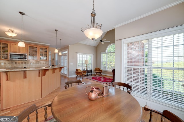 dining room with lofted ceiling, ornamental molding, a ceiling fan, light wood finished floors, and baseboards