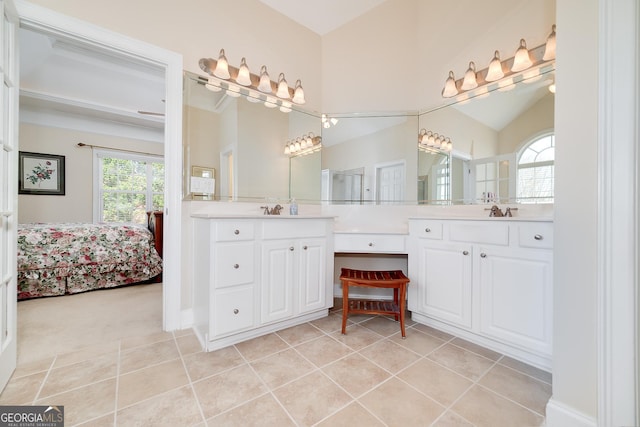 ensuite bathroom with connected bathroom, vanity, tile patterned flooring, and vaulted ceiling