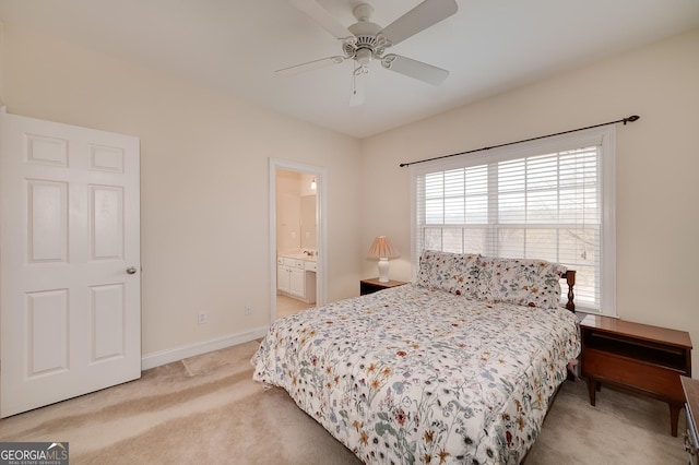 bedroom featuring light colored carpet, ensuite bath, baseboards, and a ceiling fan