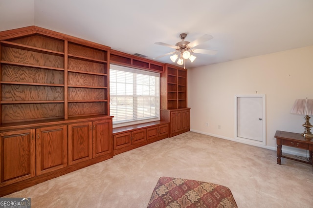 interior space featuring visible vents, light colored carpet, baseboards, and ceiling fan