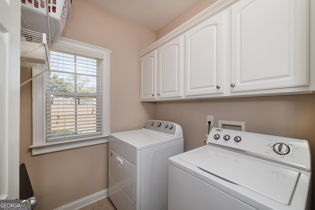 clothes washing area with washer and dryer, cabinet space, and baseboards