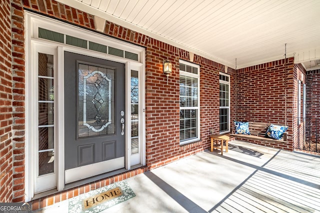 view of exterior entry with covered porch and brick siding