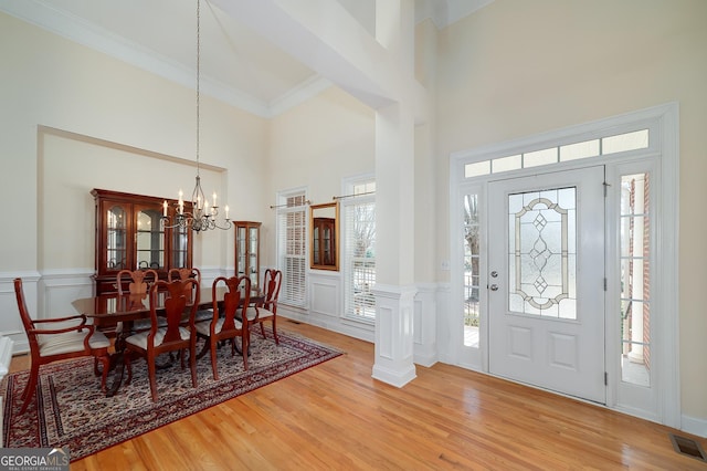 entryway with a wealth of natural light, a notable chandelier, light wood-style flooring, and visible vents