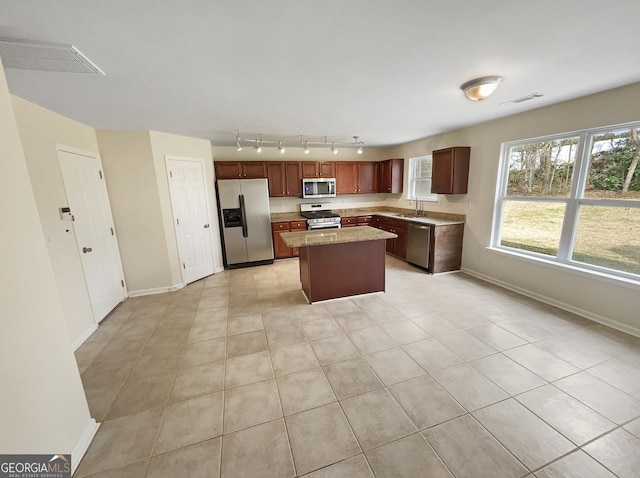 kitchen featuring visible vents, a center island, baseboards, stainless steel appliances, and a sink