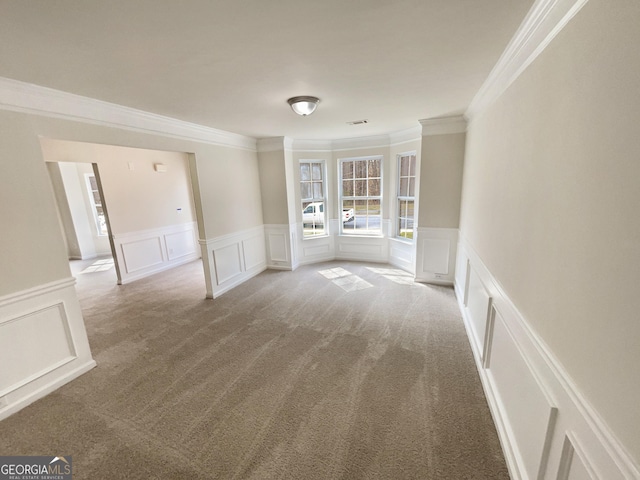 unfurnished room featuring carpet floors, ornamental molding, and a decorative wall