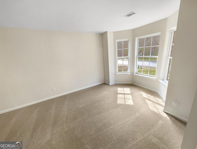 empty room with carpet flooring, visible vents, and baseboards