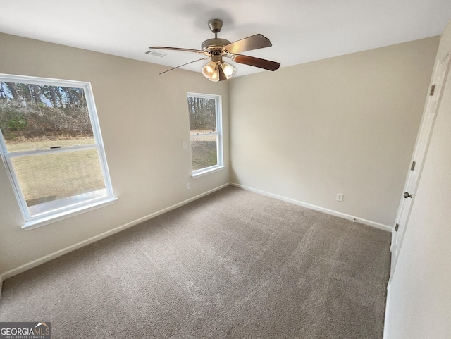 carpeted spare room with visible vents, baseboards, and a ceiling fan