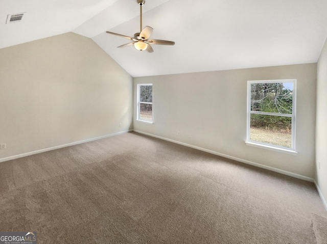 carpeted empty room with vaulted ceiling, a ceiling fan, visible vents, and baseboards