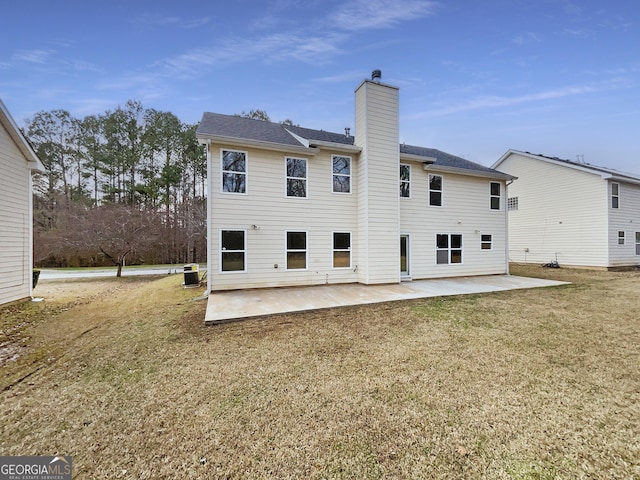 rear view of house with a patio, cooling unit, a yard, and a chimney