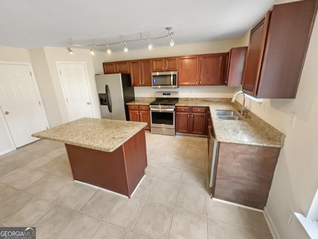 kitchen featuring light stone counters, baseboards, a kitchen island, a sink, and appliances with stainless steel finishes