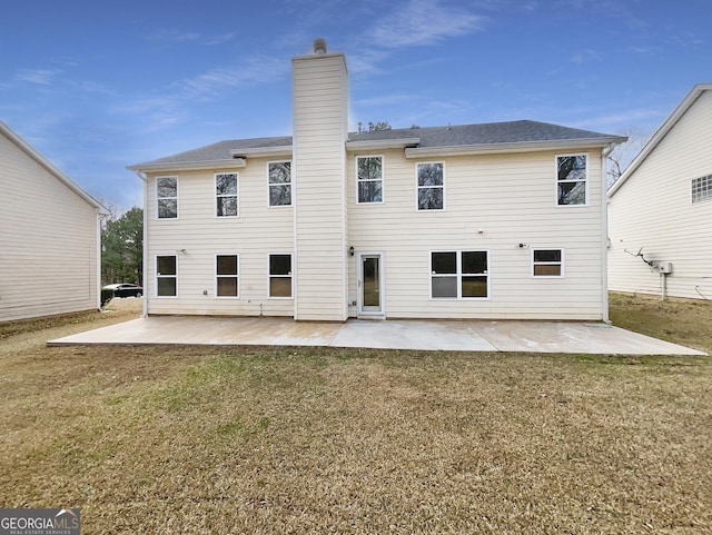 rear view of property with a patio, a yard, and a chimney