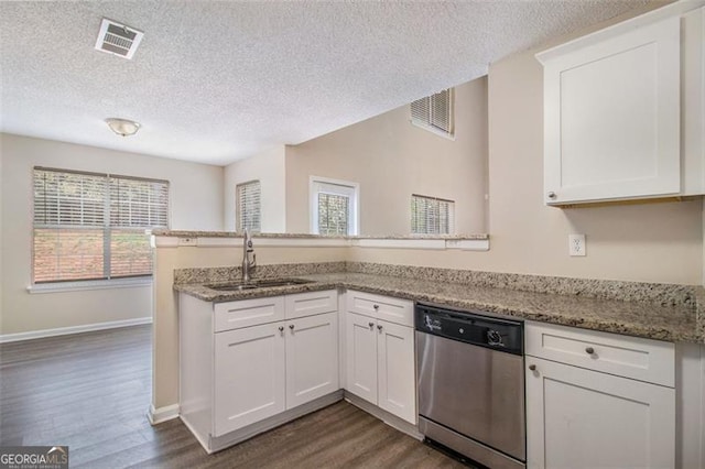 kitchen with stainless steel dishwasher, a peninsula, visible vents, and a sink