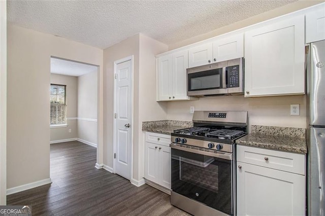 kitchen with baseboards, stainless steel appliances, dark wood-style floors, stone countertops, and white cabinetry