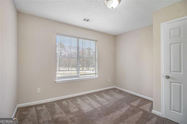 carpeted empty room featuring baseboards, visible vents, and a textured ceiling