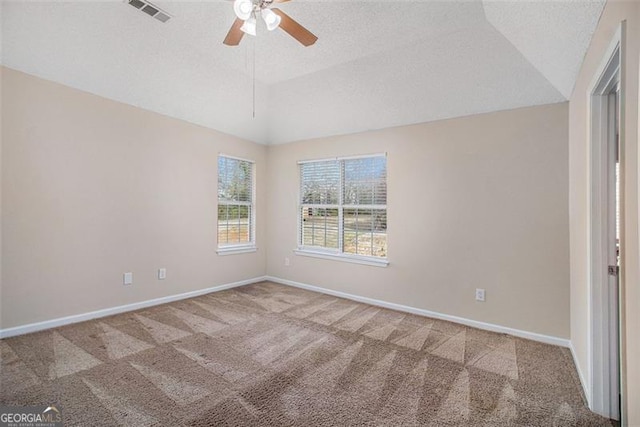 carpeted empty room with visible vents, baseboards, ceiling fan, vaulted ceiling, and a textured ceiling