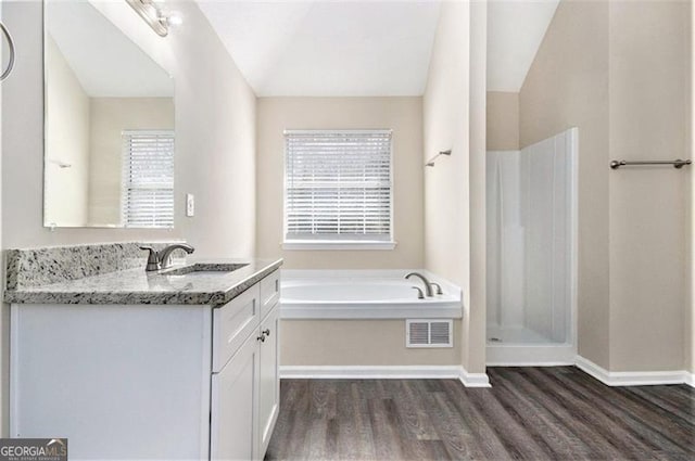 full bath featuring visible vents, wood finished floors, walk in shower, a bath, and vanity