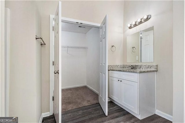 bathroom featuring baseboards, vanity, wood finished floors, and a spacious closet