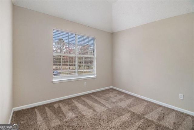 carpeted empty room featuring baseboards and lofted ceiling