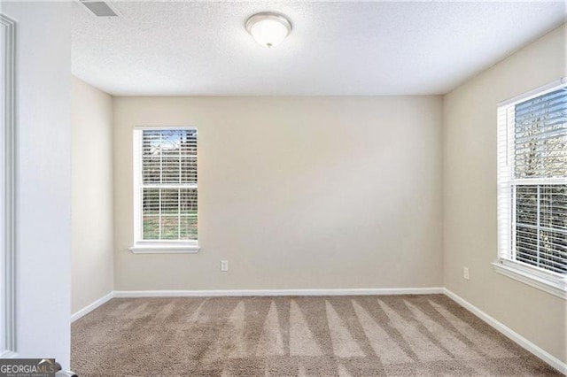 carpeted empty room with visible vents, baseboards, and a textured ceiling