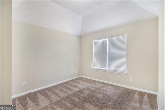 empty room featuring baseboards, carpet floors, and vaulted ceiling