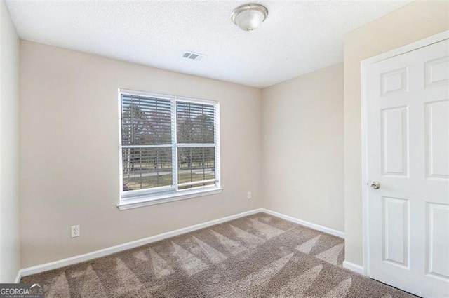 carpeted empty room with visible vents, a textured ceiling, and baseboards