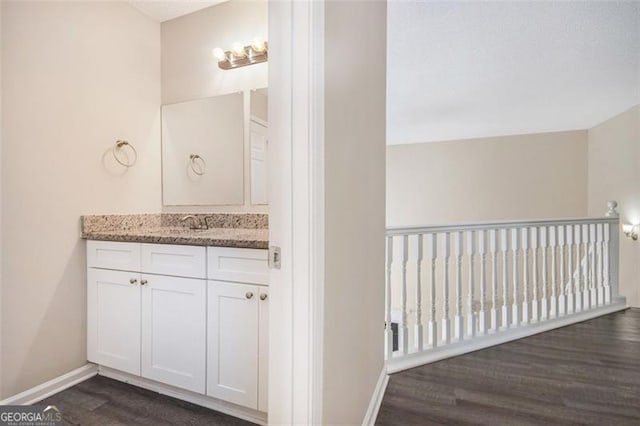 bathroom featuring baseboards, wood finished floors, and vanity