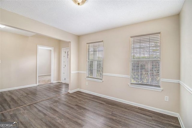 spare room featuring wood finished floors, baseboards, and a textured ceiling