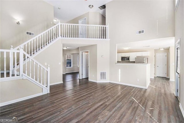 unfurnished living room with wood finished floors, visible vents, and baseboards