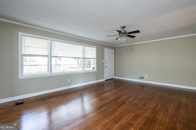 empty room with dark wood-type flooring, a ceiling fan, visible vents, and ornamental molding