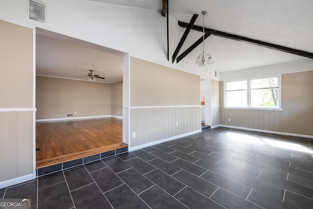 empty room with a wainscoted wall, ceiling fan with notable chandelier, vaulted ceiling with beams, and dark tile patterned flooring