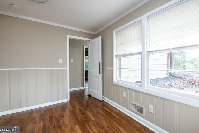 spare room with wood finished floors, crown molding, a healthy amount of sunlight, and wainscoting