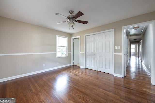 unfurnished bedroom featuring a closet, baseboards, dark wood finished floors, and a ceiling fan