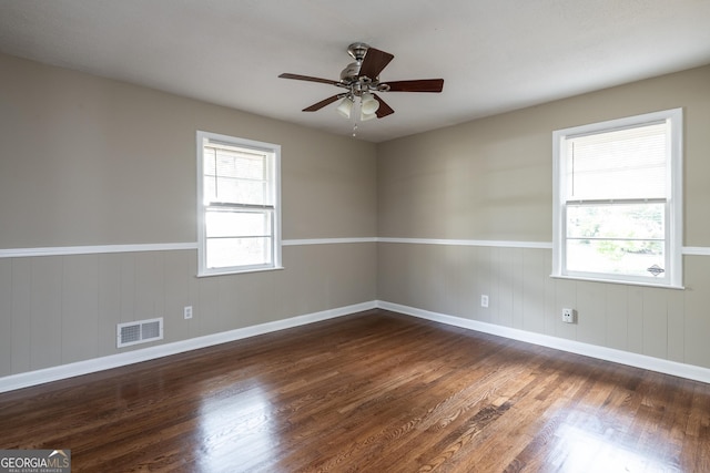 spare room featuring a wealth of natural light, visible vents, and wood finished floors