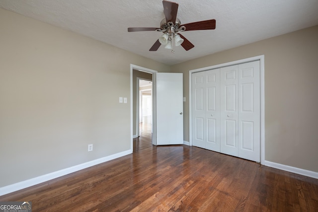 unfurnished bedroom featuring a closet, baseboards, a textured ceiling, and wood finished floors