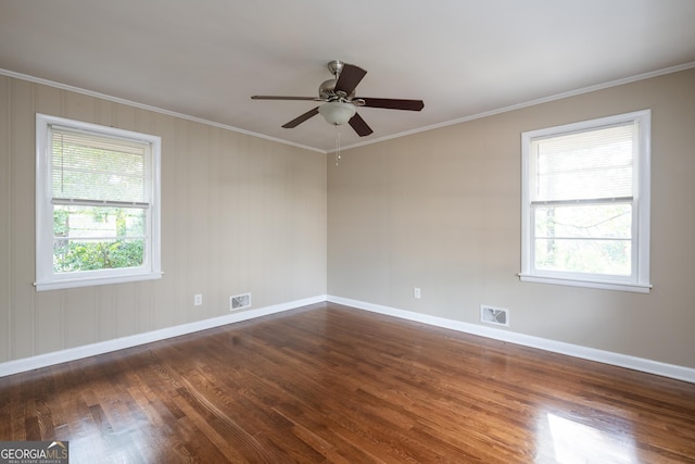 spare room featuring a wealth of natural light, visible vents, a ceiling fan, and dark wood-style flooring